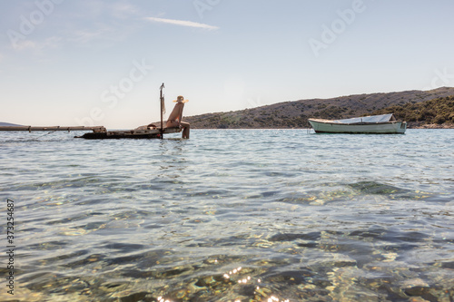 View of unrecognizable woman wearing big summer sun hat tanning topless and relaxing on old wooden pier in remote calm cove of Adriatic sea, Croatia.