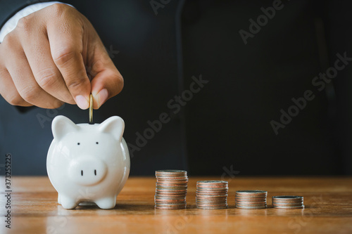 Businessmen put coins in a piggy bank, the concept of saving money and saving money for the future.