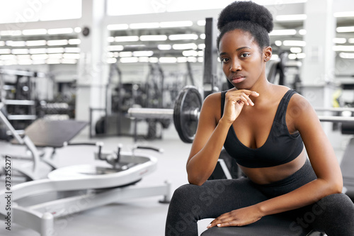 crossfit african woman sitting at gym, resting, taking a break after cross-fit workout with barbell. power, strength, healthy lifestyle, sport concept © alfa27