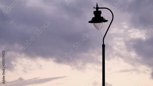 Day to night time lapse of a street lamp turning on as the day turns to dark
