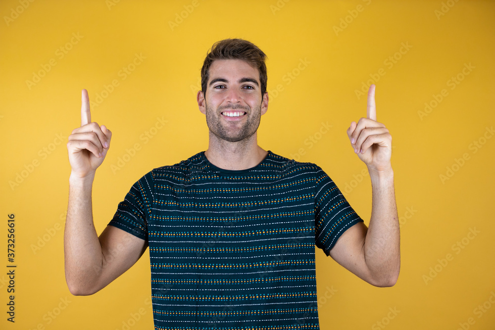 Young handsome man over isolated background smiling with happy face pointing up with two fingers Young handsome man over isolated background smiling with happy face pointing up with two fingers