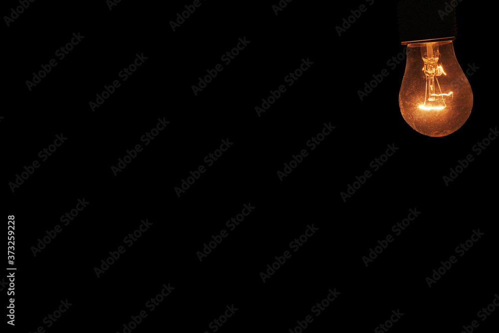 burning light bulb on black background with free space for text burning light bulb on black background with free space for text
