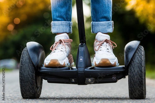 A young hipster girl driving a hoverboard outdoors in a Park, an active woman balancing on a modern electric Board, the concept of the future, alternative transport, ecology and the environment.