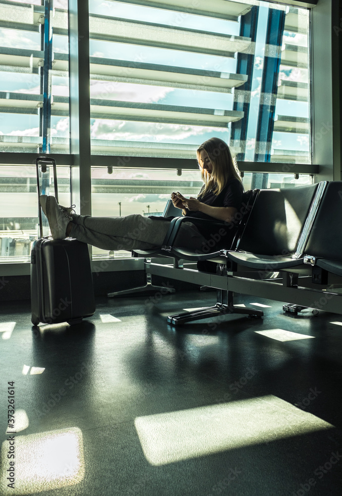 Woman waiting aircraft in airport. Young Female tourist traveling using her smartphone device. Online registration in mobile application. Woman waiting aircraft in airport. Young Female tourist traveling using her smartphone device. Online registration in mobile application.
