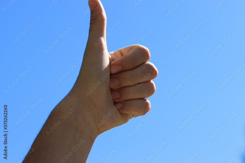 Thumb up against on the background of the sky