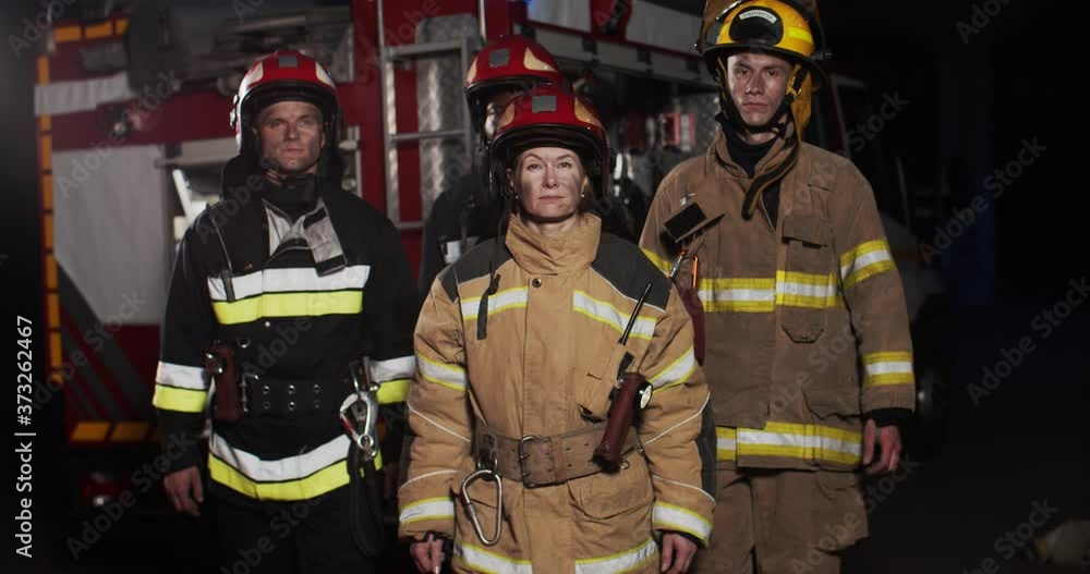 Middle plan of four firefighters approaching from fire van wearing full ...