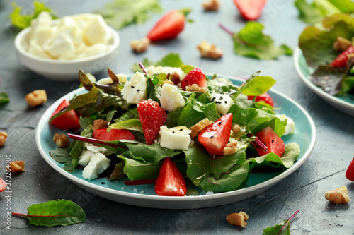 Goats cheese and strawberry summer salad served with nigella and sesame seeds drizzled with runny honey
