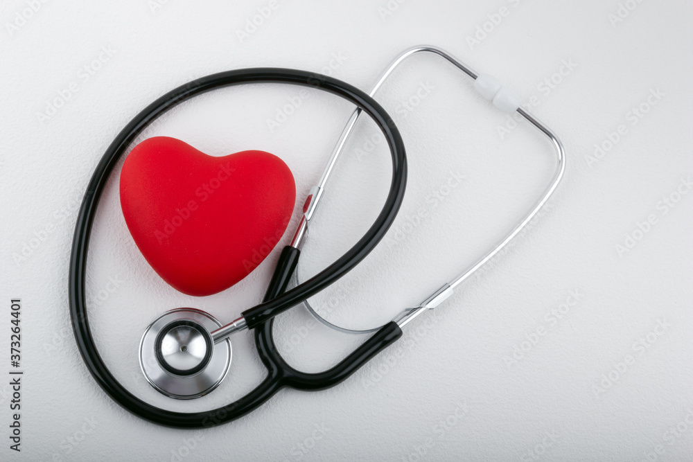 Stethoscope and red heart on white table, closeup. Medicine concept.