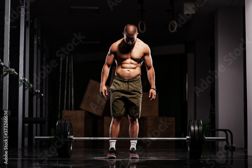 Muscular athlete preparing to lift barbell. Crossfit trainer in a fitness studio.