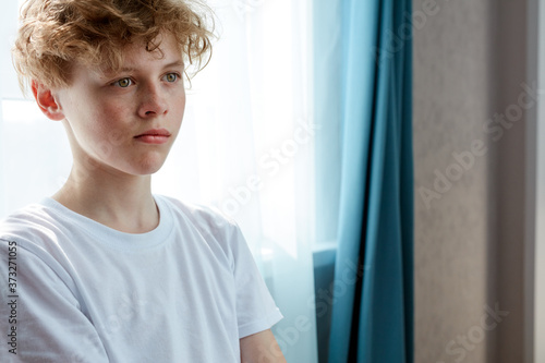 portrait of thoughtful serious boy with natural red hair, boy in contemplation