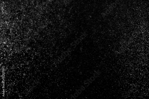 Abstract splashes of water on black background. Freeze motion of white particles. Rain, snow overlay texture.