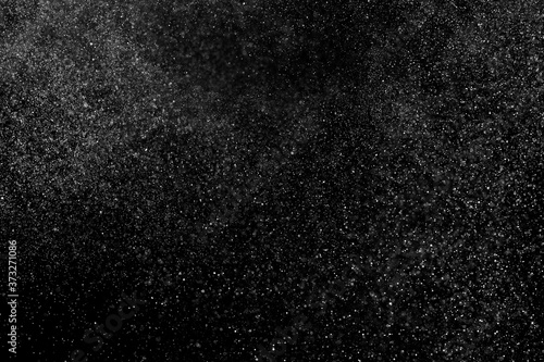 Abstract splashes of water on black background. Freeze motion of white particles. Rain, snow overlay texture.