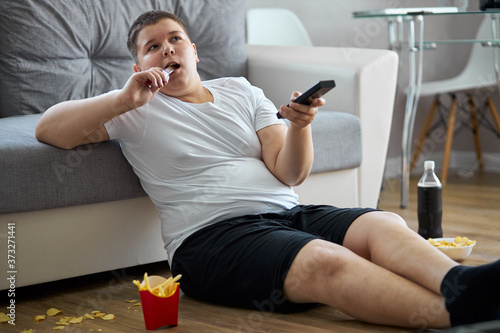 Foto fat overweight teenager boy has bad nutrition, eat unhealthy food
