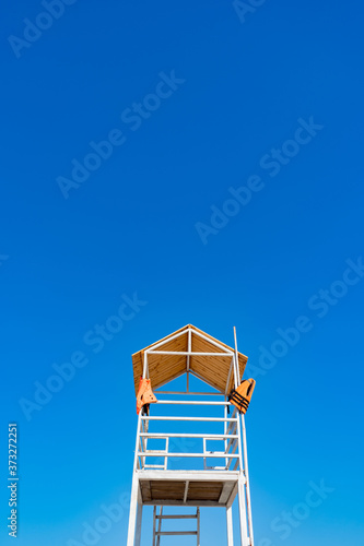 white wooden lifeboat tower on beach against sky.