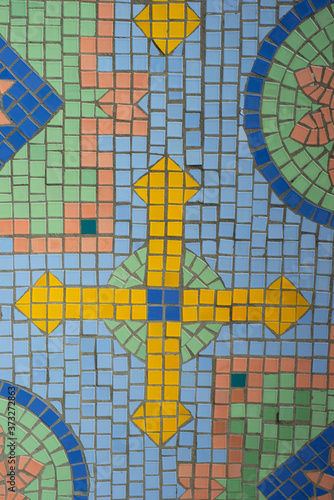  Mosaic ornament with a cross. Small colored tiles are folded into a pattern.