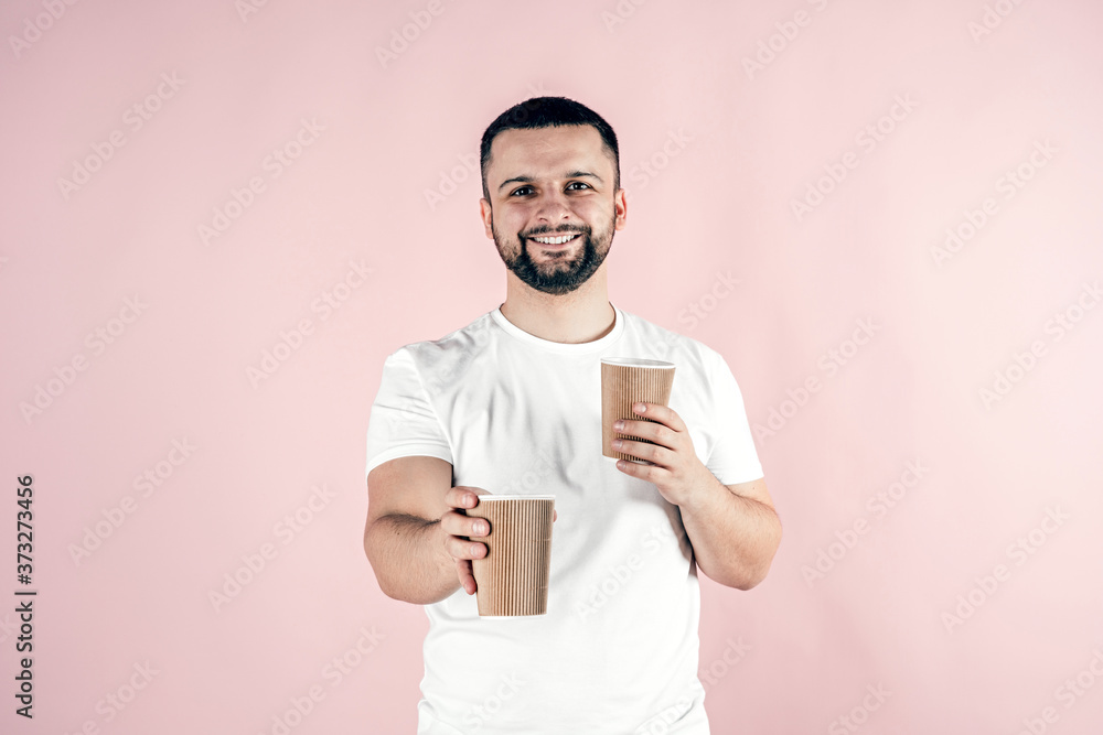 A young man holds a paper cup in his hands. A young man holds a paper cup in his hands.