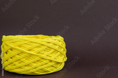 yellow t-shirt yarn ball on brown background. Handmade craft recycle eco concept