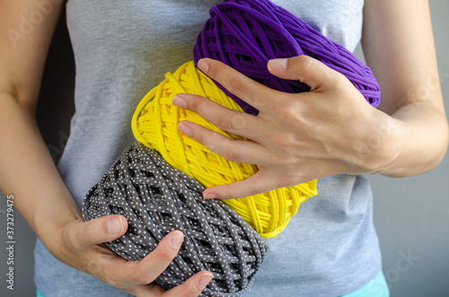 female hands holding big purple, yellow and gray t-shirt yarn balls. Handmade, craft, recycle, eco concept