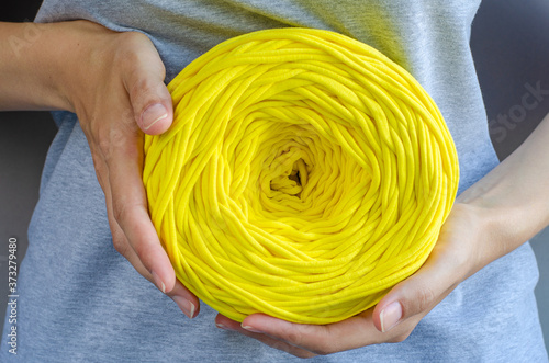 female hands holding big yellow t-shirt yarn ball. Handmade, craft, recycle, eco concept