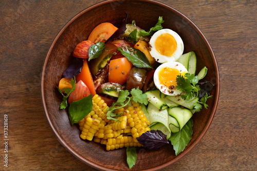 Corn salad with vegetables and boiled egg, top view, copy space