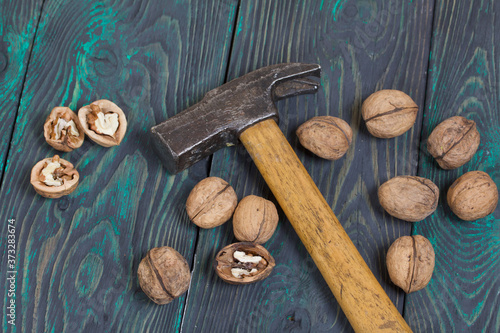 Walnuts and a hammer. Scattered on painted pine board surfaces.