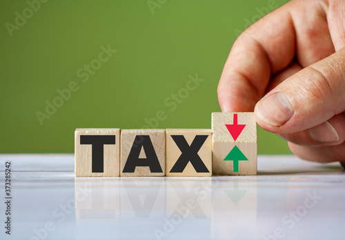 Word TAX symbol concept and hand turn wooden block and change red arrow to green