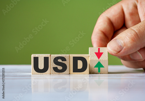 Word USD symbol concept and hand turn wooden block and change red arrow to green or vice versa