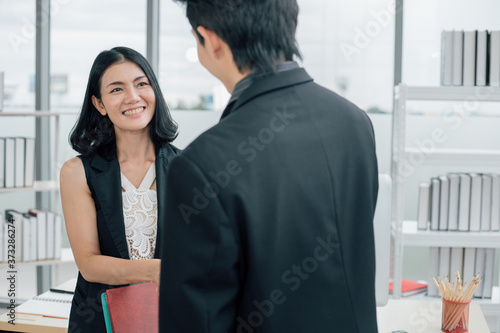 Smile asian business woman shaking hands with businessman in office during meeting.