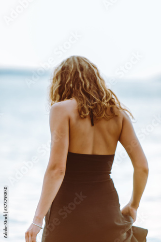 woman in black dress walking in water at sea beach © phpetrunina14