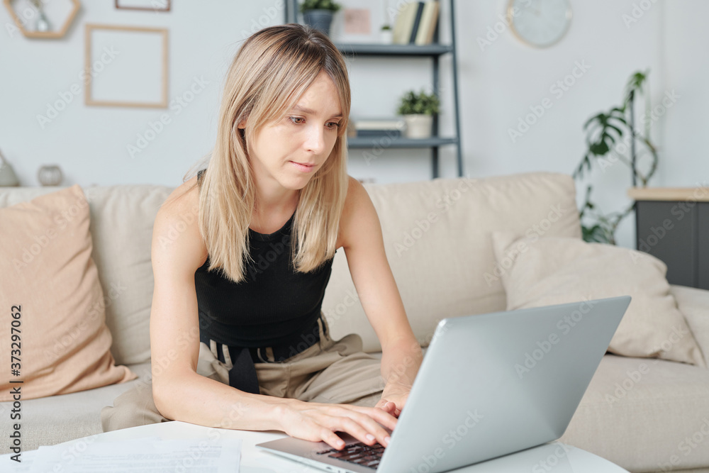 Young pretty female with long blond hair looking at data on laptop display Young pretty female with long blond hair looking at data on laptop display