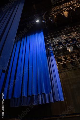 The lights of the stage overhead. Part of the backstage of the Philharmonic concert hall with lighting equipment and a blue curtain. Ceiling lighting equipment.