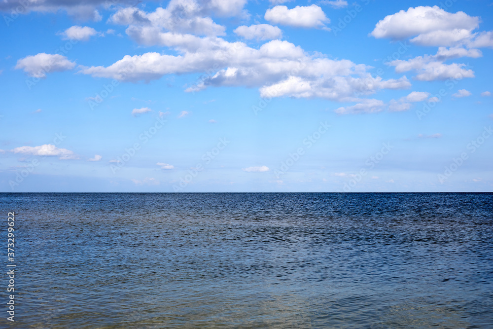 calm sea waters against a blue sky with clouds