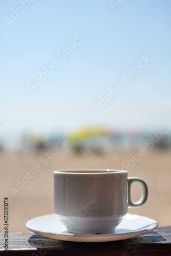 white cup with coffee drink on the background of the shore