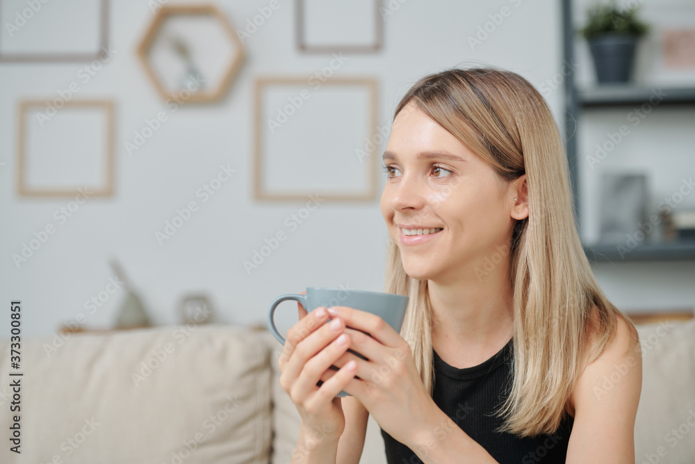 Young smiling pretty woman with mug of coffee enjoying leisure at home Young smiling pretty woman with mug of coffee enjoying leisure at home