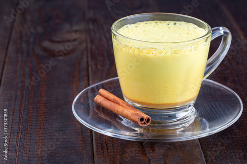 Moon milk with turmeric in a glass cup, horizontal, copy space