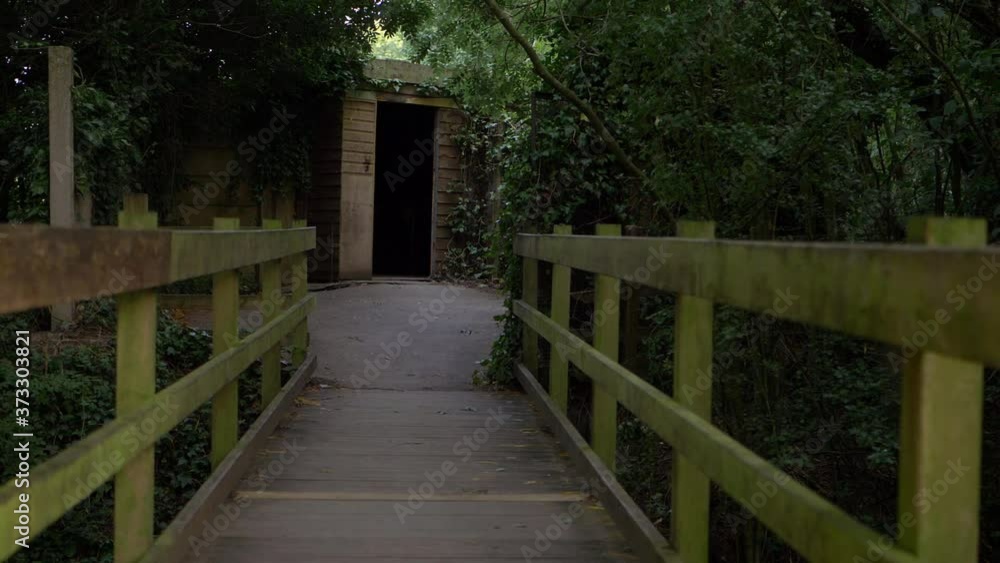 Walking over small wooden bridge leading to a doorway wide shot Walking over small wooden bridge leading to a doorway wide shot