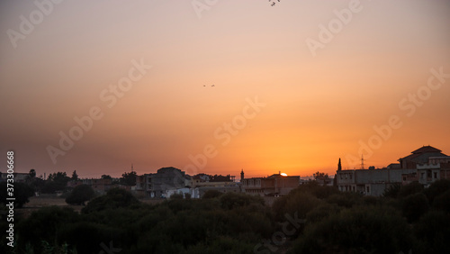 City landscape, field and city with high-rise buildings lit by the sun at sunset © Zakarya Roubache