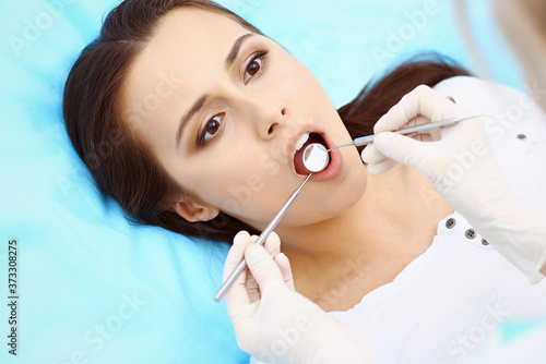 Young female patient visiting dentist office.Beautiful woman feeling fear and pain during doctor working at teeth. Dental clinic, stomatology concept