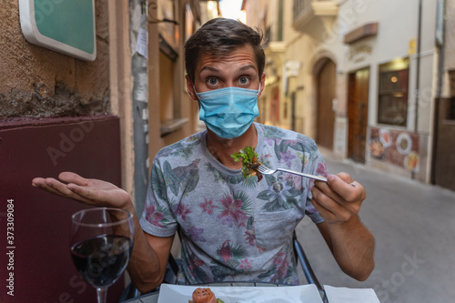 young man tries to eat with face mask in the ancient alley photo