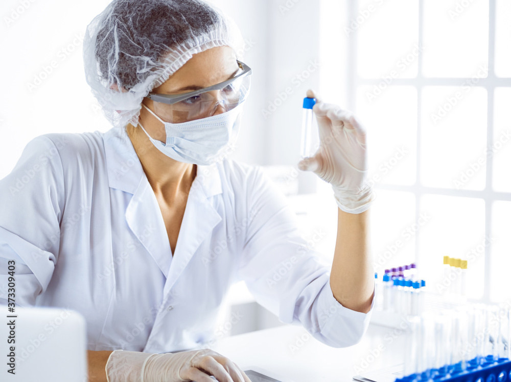 Professional female scientist in protective eyeglasses researching tube with reagents in laboratory. Concepts of medicine and science researching Professional female scientist in protective eyeglasses researching tube with reagents in laboratory. Concepts of medicine and science researching