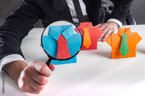 Recruiting. HR. Recruiter is looking for a pesonal. Employer holds a magnifying glass next to employee. Search for employees. Magnifier as a symbol of checking a potential employee. Recruiting people photo