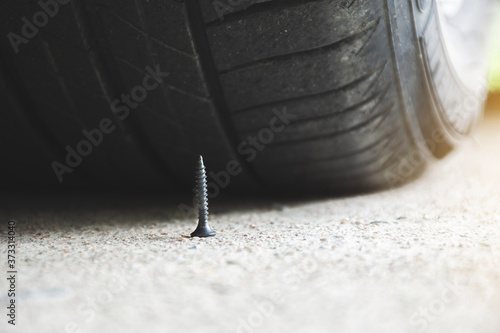 Close up of sharp metal screw on road nearly to puncture a car tire