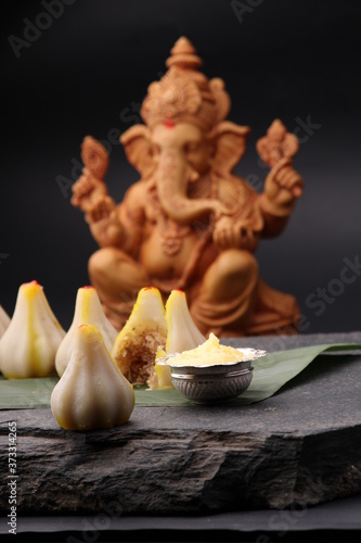 Modak- a traditional dish made on Ganpati festival in India. served with clarified butter. Ganesh idol at background photo