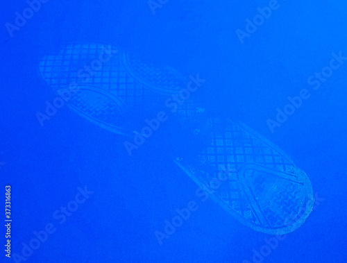 White footprint from a boot smeared with whitewash on a blue background close-up.