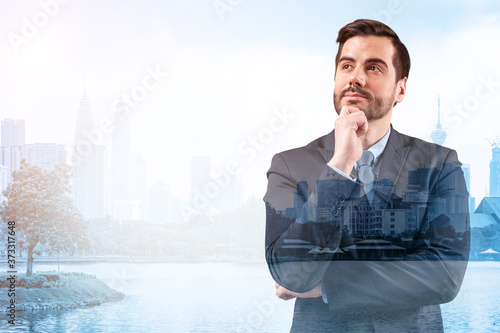 Canvas Print Young handsome businessman in suit with hand on chin thinking how to succeed, new career opportunities, MBA