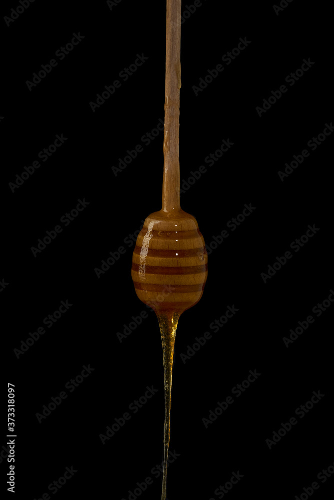 Wooden dipper with dripping honey isolated on black background, bee products by organic ingredients concept. Natural fresh honey, no additives, ready to eat Wooden dipper with dripping honey isolated on black background, bee products by organic ingredients concept. Natural fresh honey, no additives, ready to eat