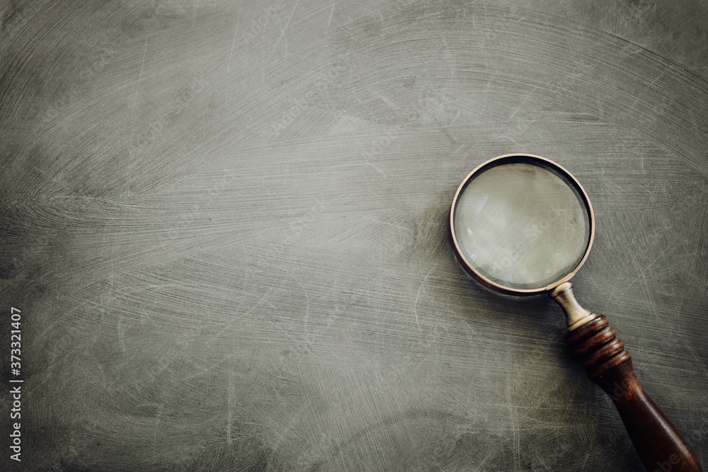 vintage magnifying glass with wooden handle over chalkboard background