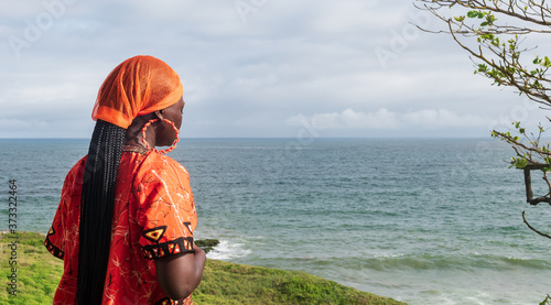 Fotografie Praying African Woman wearing orange traditional dress from Ghana looks over the