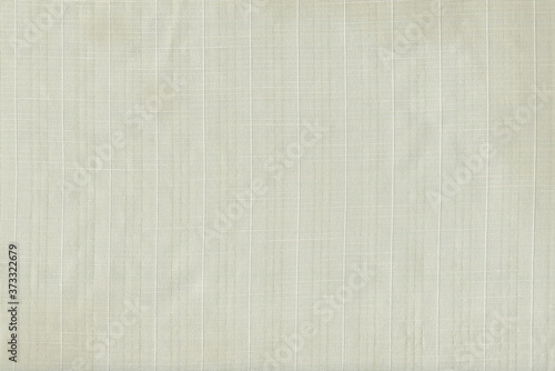 Grunge texture of light natural fabric. Abstract monochrome background of soft fabric with vertical stripes of threads.