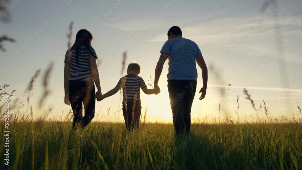 Happy family. Mom dad and son in an outdoor team walk through a green meadow at sunset. Healthy, active lifestyle of a married couple. Parents with a child have fun. Happy family. Mom dad and son in an outdoor team walk through a green meadow at sunset. Healthy, active lifestyle of a married couple. Parents with a child have fun.